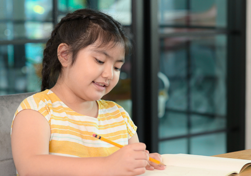 Smiling student completing homework – individualized tutoring that builds confidence and executive functioning skills in elementary learners